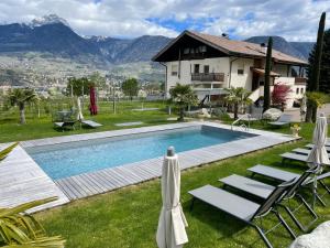 uma piscina com cadeiras e uma casa e montanhas em Garden-Suite Faselehof em Marlengo