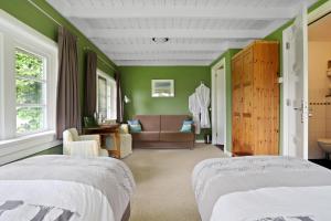 a green bedroom with two beds and a couch at B&B - Sauna D'Olle Pastorie in Vierhuizen