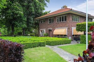 a brick house with a garden in front of it at B&B - Sauna D'Olle Pastorie in Vierhuizen