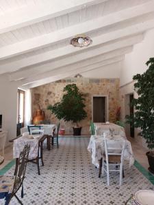 jadalnia ze stołami i krzesłami oraz kamienną ścianą w obiekcie Resort Masseria Cecato w mieście Noci