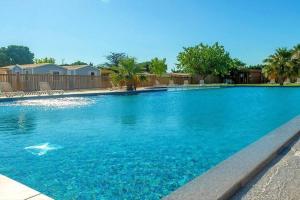 een groot zwembad met blauw water bij Mobile home tout confort Roman in Port-la-Nouvelle