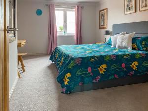 a bedroom with a bed with a floral bedspread at Chestnut House in Bridgend
