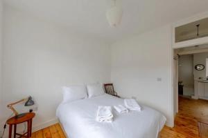 a white bed with two white towels on it at Bright 2BD Flat - 4 min walk to Hampstead Heath in London