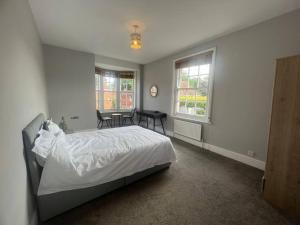 a bedroom with a bed and a table and windows at Crondall Stores Flat in Crondall