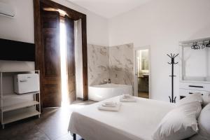a white bedroom with a tub and a bed at La bella vita luxury apartament and travel solution in Naples