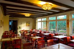 a restaurant with tables and red chairs and windows at Hotel Kölner Hof Refrath in Bergisch Gladbach