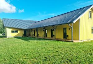 een gele schuur met een metalen dak op een grasveld bij Auksi motell in Auksi