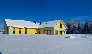 een geel en groen gebouw in de sneeuw bij Auksi motell in Auksi