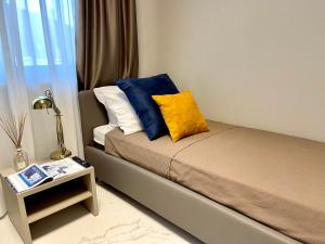 ein kleines Schlafzimmer mit einem Bett mit blauen und gelben Kissen in der Unterkunft Darsena Luxury apartments in Viareggio