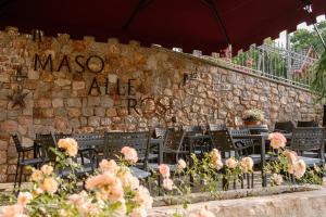 una pared de piedra con mesas, sillas y flores en Agritur Maso alle Rose B&B e Restaurant, en Fiavè