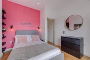 Habitación de color rosa con cama y espejo en The Lipstick Palace - Fitzrovia - by Frankie Says en Londres