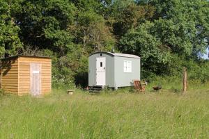 ein kleiner Schuppen und ein Haus auf einem Feld in der Unterkunft Cattlestone Farm in Coolham