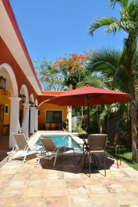 a patio with chairs and an umbrella and a pool at VILLA UNAHANA in Valladolid