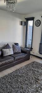 a brown leather couch in a living room with a rug at The Cwtch in Cardiff