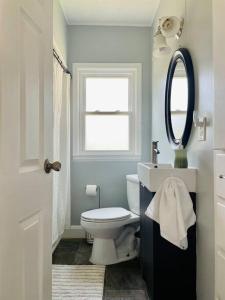 La salle de bains est pourvue de toilettes blanches et d'un miroir. dans l'établissement Green Roof Inn - Centrally Located 2BR/1BA Home, à Evansville