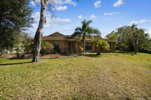 a house with a tree in the yard at TRANQUILITY! PRIVATE Gated Estate! Boats, RVs OK! Has Separate Apt, Fishing, Hiking, LOW Rates! in Kissimmee