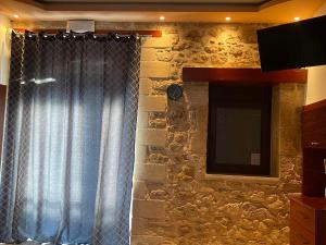a stone wall with a curtain and a television at Anna's room in Archanes