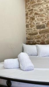 a bed with white pillows and a brick wall at Anna's room in Archanes