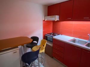 a kitchen with red cabinets and yellow chairs in it at Anna's room in Archanes