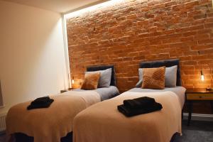 duas camas num quarto com uma parede de tijolos em Entire house in Retford city centre em Retford