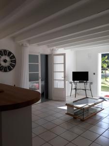 a living room with a table and a clock on the wall at Amarante des Landes in Cap de Pin