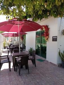 un patio con tavoli, sedie e ombrelloni di Apartahotel Eden Coveñas a Coveñas