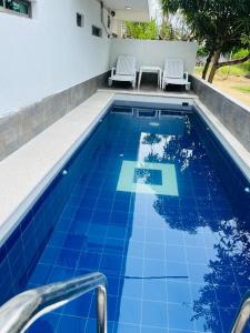 a swimming pool with a blue tile floor and two chairs at Apartahotel Eden Coveñas in Coveñas