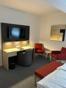 a hotel room with a tv and a desk and chairs at Hotel Kaiserhof in Siegburg