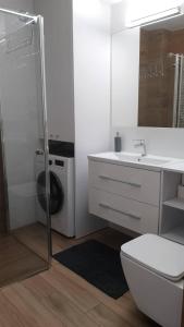 a bathroom with a toilet and a sink and a washing machine at Apartament Zalesie z tarasem in Lubin