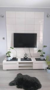 a white entertainment center with a flat screen tv and plants at Apartament Zalesie z tarasem in Lubin
