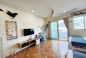 una camera con letto, TV e balcone di Sun Shine B&B a Città Vecchia di Hengchun