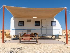 a trailer with a picnic table in front of it at Itav Bateva Caravans - ייטב בטבע קרוואנים in Mitzpe Ramon