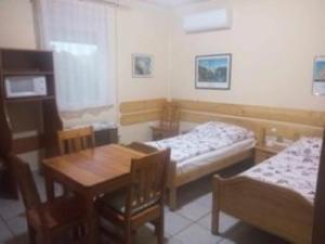 a room with two beds and a table and chairs at Pelikán Szállás in Nagykanizsa