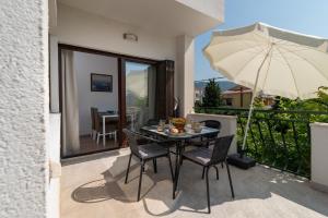 einen schwarzen Tisch mit Stühlen und einem Sonnenschirm auf dem Balkon in der Unterkunft Apartment East in Kaštela