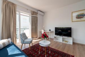 ein Wohnzimmer mit einem Sofa und einem TV in der Unterkunft Apartment East in Kaštela