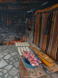 a stone fireplace with a table with meat in front of it at Guest House Temi In Gudani 