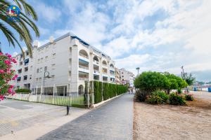 a white building on the beach with a palm tree at Apartamentos La Noria Casa Azahar in Alcossebre