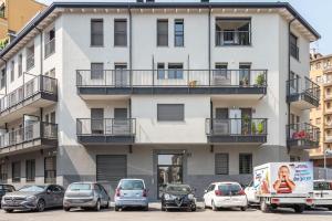 un bâtiment blanc avec des voitures garées devant lui dans l'établissement Kaizen House - Bilocale De Angeli, à Milan