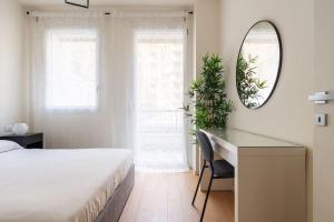 - une chambre avec un lit, un bureau et un miroir dans l'établissement Kaizen House - Bilocale De Angeli, à Milan