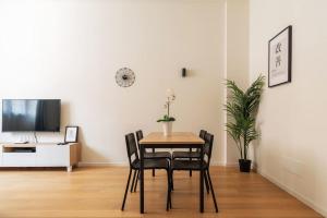 - une salle à manger avec une table, des chaises et une télévision dans l'établissement Kaizen House - Bilocale De Angeli, à Milan