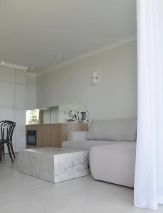 Una sala de estar blanca con un sofá y una mesa. en Rewal HEVENIA Premium Baltic Apartment with SPA access, en Rewal