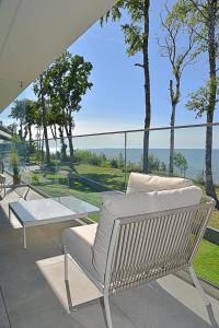 una silla blanca sentada en un patio con vistas al océano en Rewal HEVENIA Premium Baltic Apartment with SPA access, en Rewal