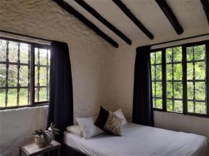 a bedroom with two beds and two windows at Villa Calusa in Villeta