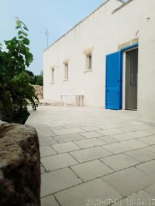 um edifício branco com uma porta azul e um pátio em Domus Veretum em Morciano di Leuca