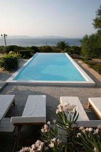 a swimming pool with two chairs and a table at Pines & Sea Studio in Áyioi