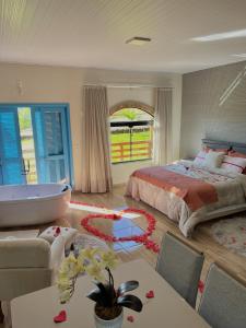 a bedroom with a bed and a tub and a table at Pousada Di Venezia - Hotel Fazenda in Nova Veneza