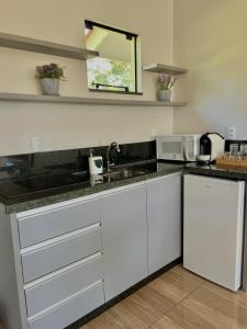 a kitchen with white cabinets and a sink and a microwave at Pousada Di Venezia - Hotel Fazenda in Nova Veneza