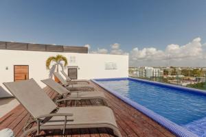 a group of chairs sitting on a deck next to a swimming pool at Moderno y amplio estudio en el centro de Playa in Playa del Carmen