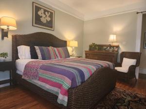 a bedroom with a bed with a blanket and a chair at Rosemont B&B Cottages in Little Rock
