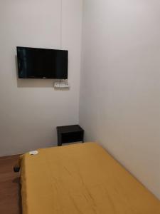 a bedroom with a bed and a flat screen tv on the wall at G FORTUNE HOTEL + in George Town